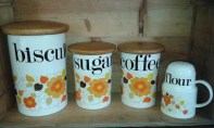 Biscuit, sugar & coffee cannisters in cream with orange flower decoration & wooden lids & matching flour shaker.